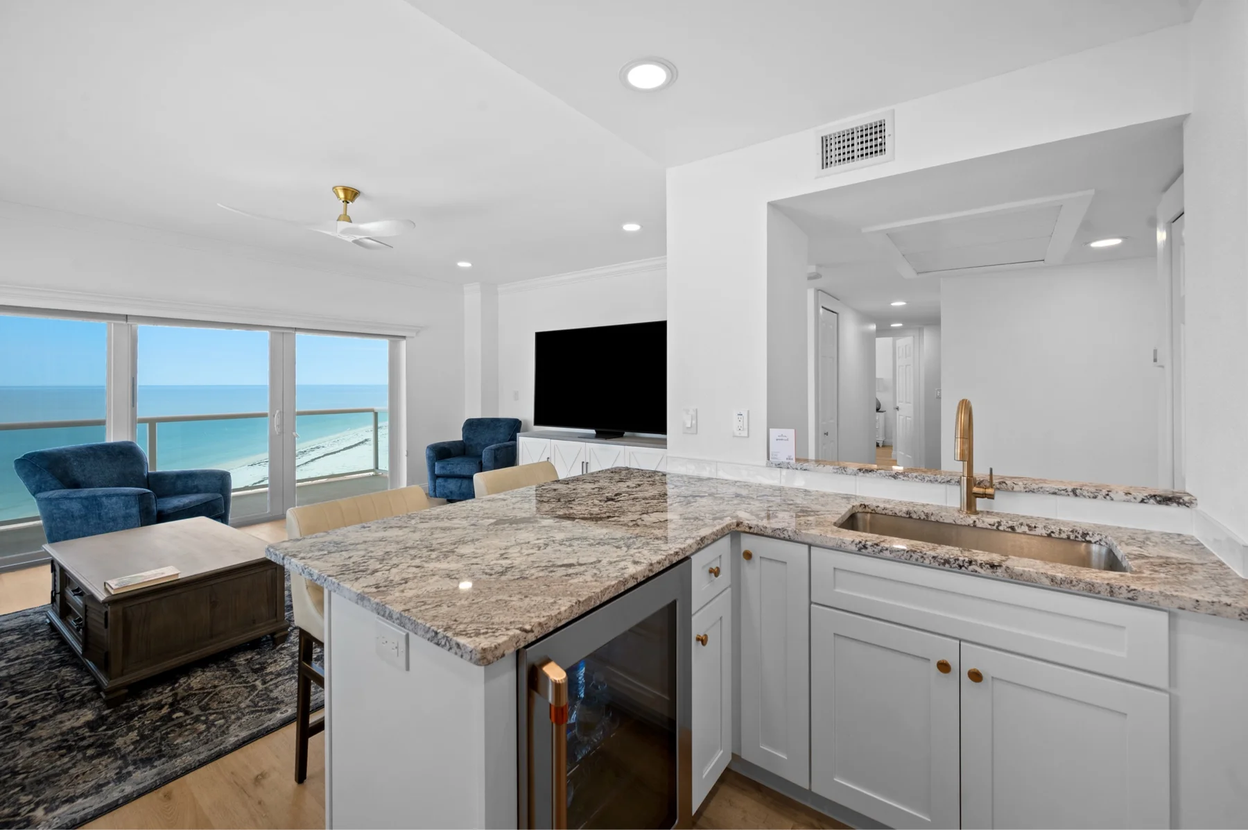 Bright white shaker kitchen cabinets with gold hardware and an ocean view